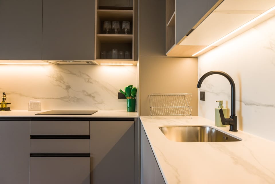 Sleek and modern kitchen with marble countertops and ambient lighting, perfect for culinary enthusiasts.