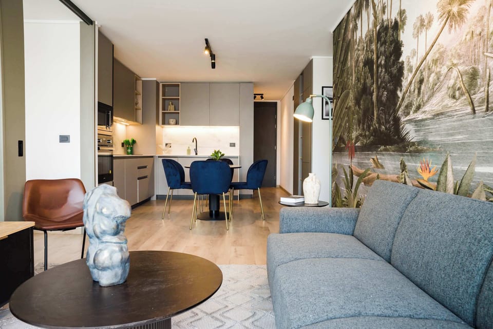 Stylish open-plan living area with chic decor and a vibrant mural, perfect for relaxation and dining.