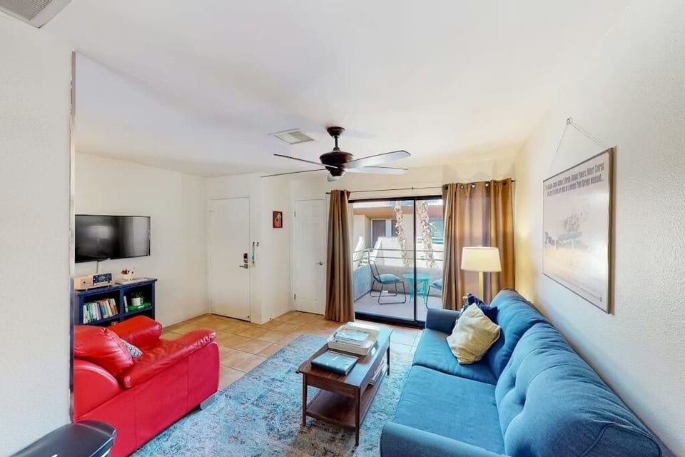 Bright living room with sofa bed, smart TV, and balcony access