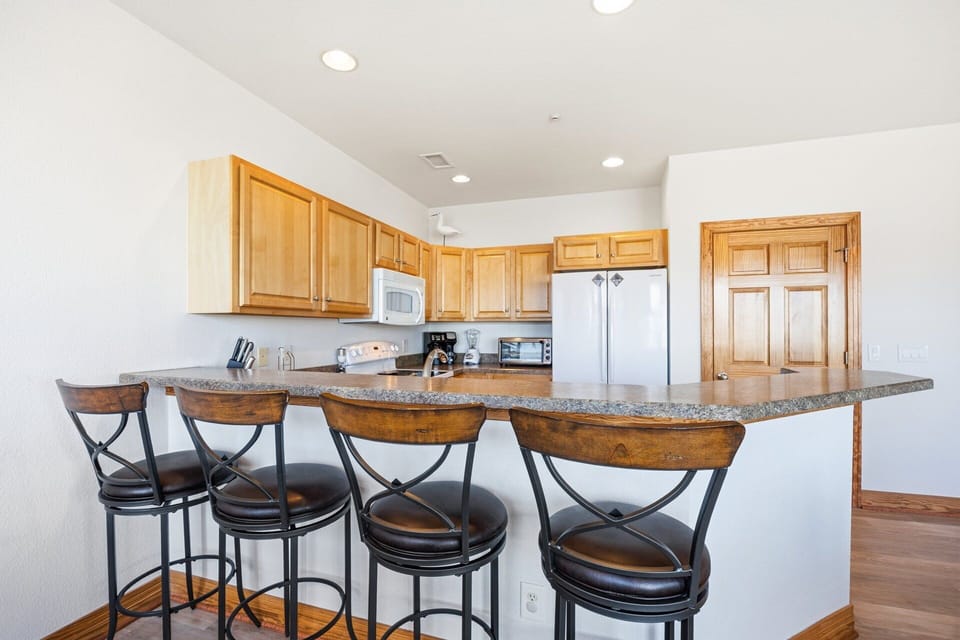The fully equipped kitchen includes modern appliances and a breakfast bar, making meal prep easy and enjoyable during your stay.