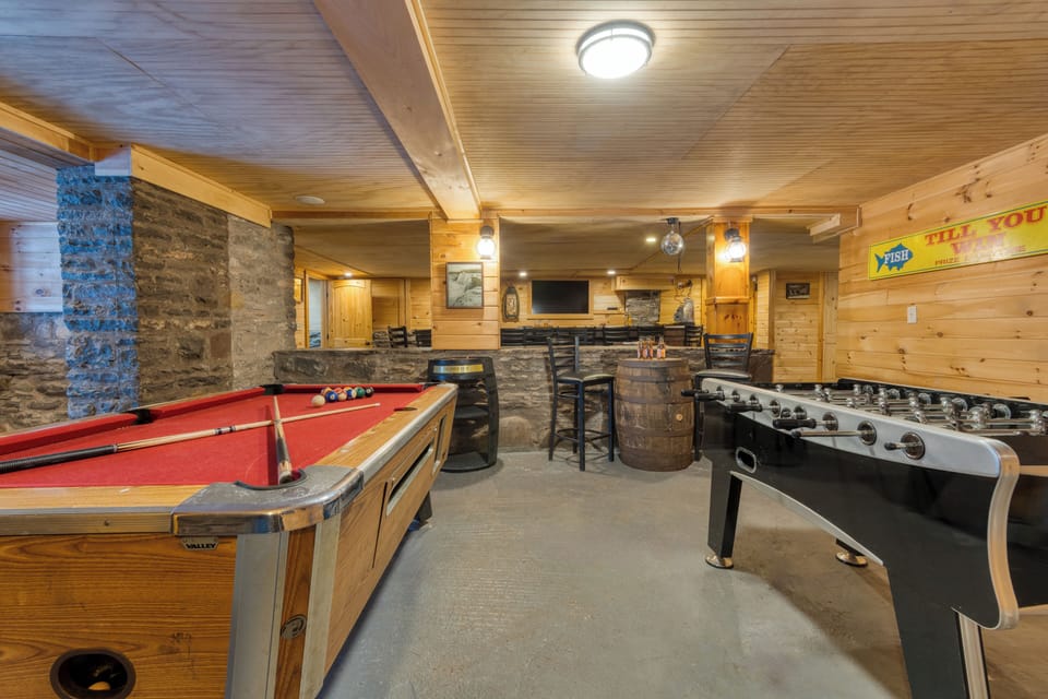 Basement lounge area with pool table, TV, and foosball table.