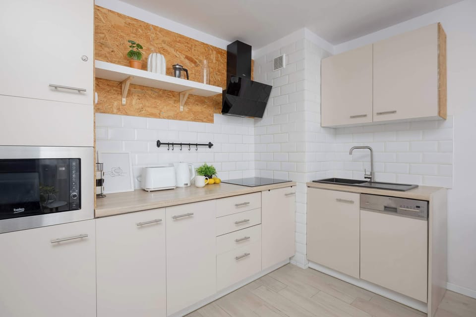 Modern kitchen with white cabinetry, wooden accents, tiled backsplash, and built-in appliances.