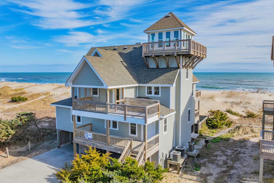 Beachfront vacation home with crow's nest tower and multiple decks, offering direct beach access and panoramic ocean views.