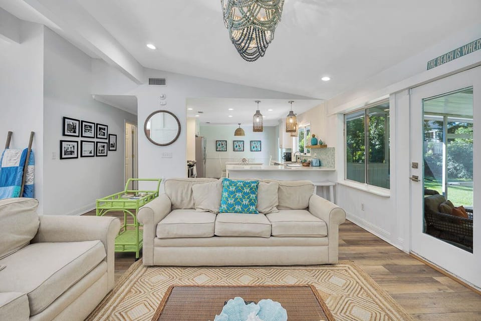 Living Room with Kitchen and Screened Porch Access – 530 Delegal - Alternate view of the main house living room at 530 Delegal showing seating facing the kitchen area behind the couch and glass doors opening to the screened porch.