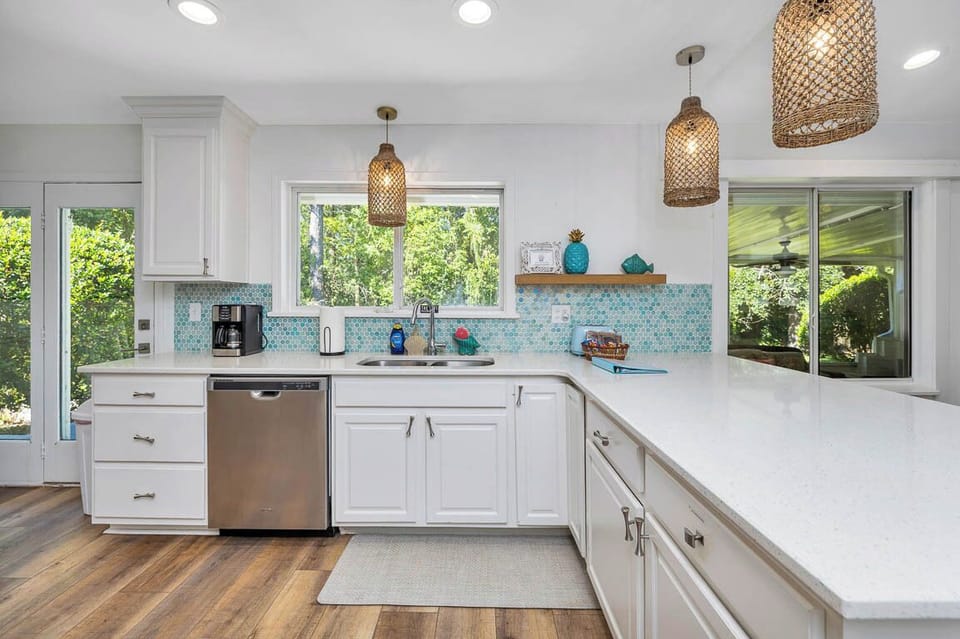Main House Kitchen Workspace - Long counters, sink, dishwasher, open shelving, and windows toward the screened porch support meals for a full house.