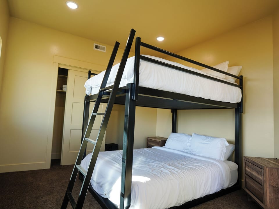 Your stylish bunk bed setup offers comfortable sleeping for four with crisp linens and modern metal frames in a warm, well-lit room.