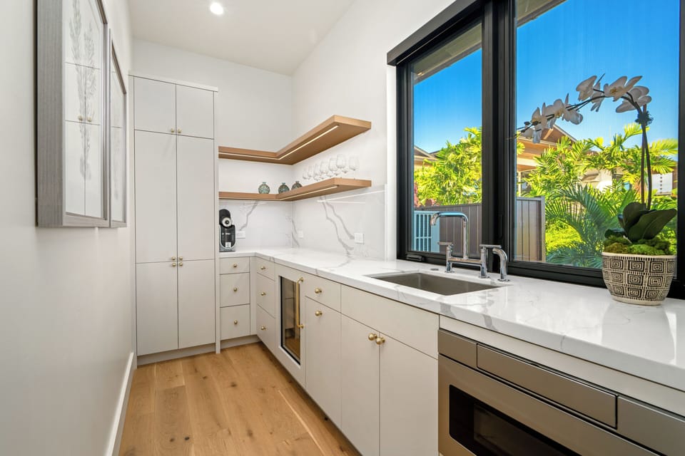 This modern kitchen features marble countertops and garden views, perfect for preparing meals while enjoying tropical greenery outside.