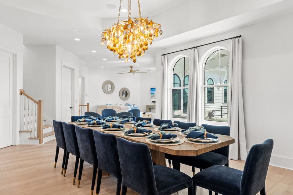Gather around your stunning dining table beneath a show-stopping chandelier, where elegant navy chairs and thoughtful place settings await your memorable meals together.