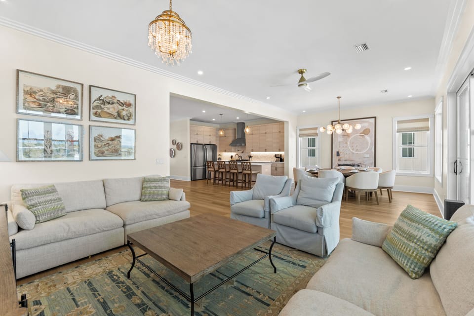 Sink into plush seating in your bright, elegant living room, where a chandelier and open layout connect you seamlessly to the kitchen and dining spaces—perfect for gathering and unwinding.