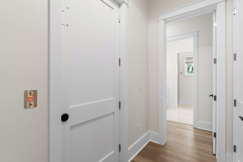 A bright hallway leads through multiple doorways, opening up sight lines through the home, with light streaming in from beyond.