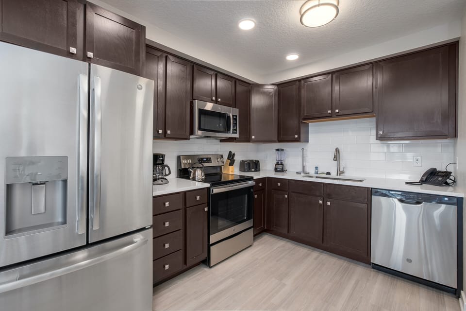 Your fully equipped kitchen features rich dark cabinetry, gleaming stainless steel appliances, and pristine countertops perfect for preparing memorable meals.