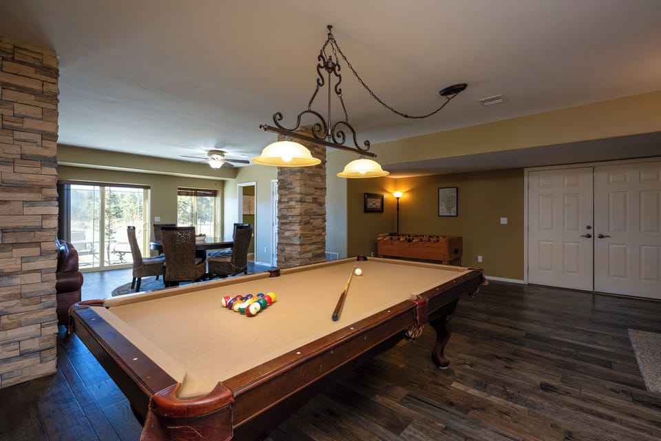 Challenge friends to a game in your spacious entertainment room, featuring a professional pool table beneath warm pendant lighting.