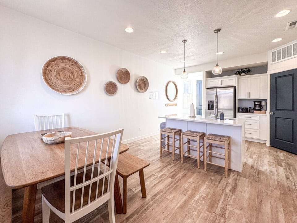 Bright modern kitchen-dining space with coastal touches, island seating, wood floors, perfect for relaxing stays.