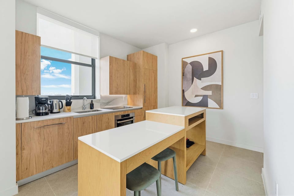 The kitchen features a modern breakfast bar equipped with chic bar stools, offering the perfect spot for a casual morning coffee or a quick bite before heading out to explore Miami.