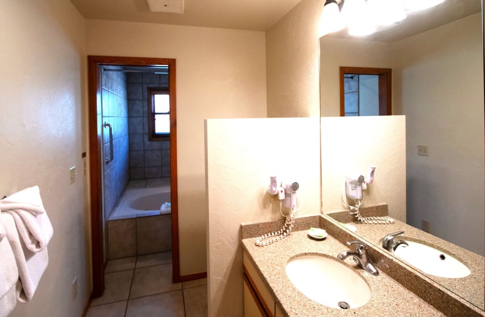 Step into a well-appointed bathroom featuring a spacious double vanity and convenient access to the relaxing jetted tub beyond.