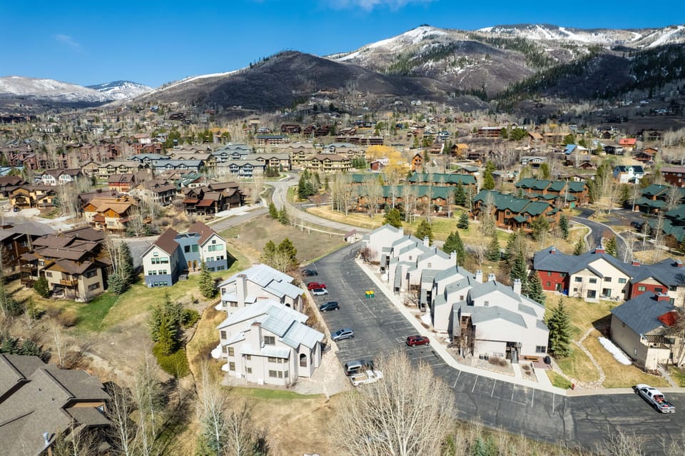 An aerial view captures a scenic community with colorful homes nestled among rolling hills and mountains.