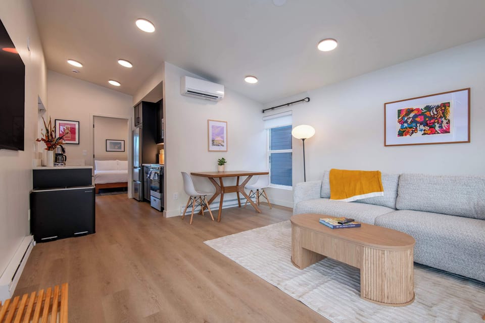 Bright open layout with living space, dining for two, kitchen, and a private bedroom.