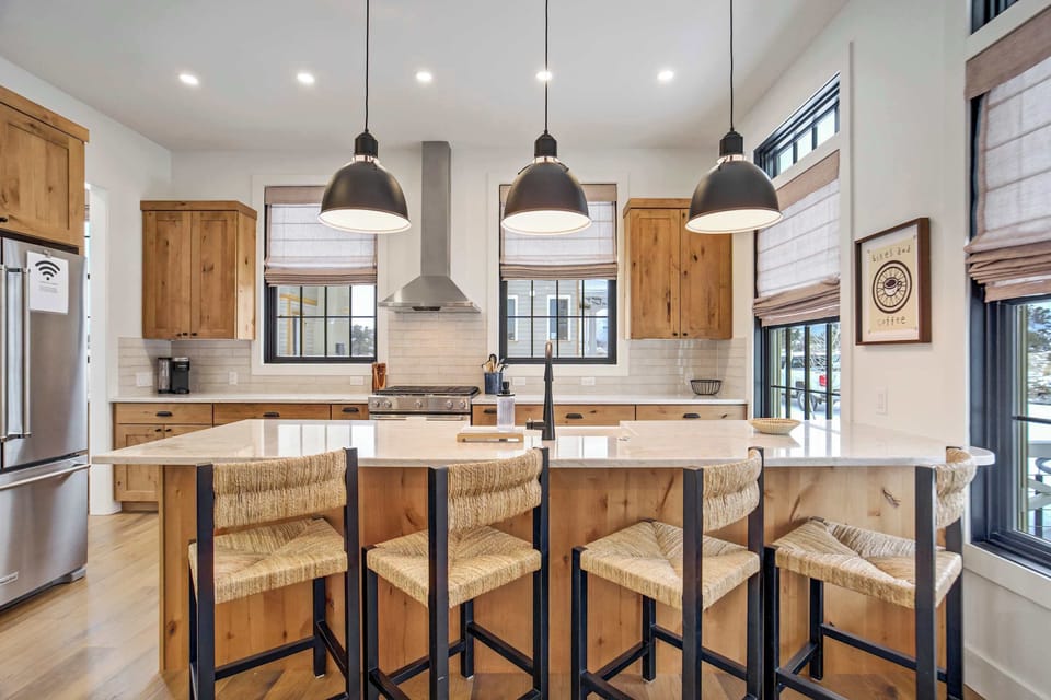 The gourmet kitchen features a large center island with a farmhouse sink and casual breakfast bar seating for four. Professional-grade stainless steel appliances, including a gas range, are paired with elegant stone countertops and warm wood cabinetr