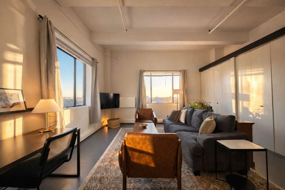 Welcome to your sun-drenched corner studio, featuring a plush queen bed and wall-to-wall windows