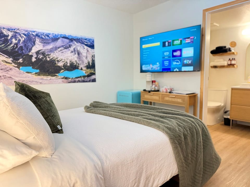 Cozy Lower Suite: A restful bedroom featuring a 55-inch Smart TV and electric fireplace, designed for couples or singles seeking a "hotel-style" stay.