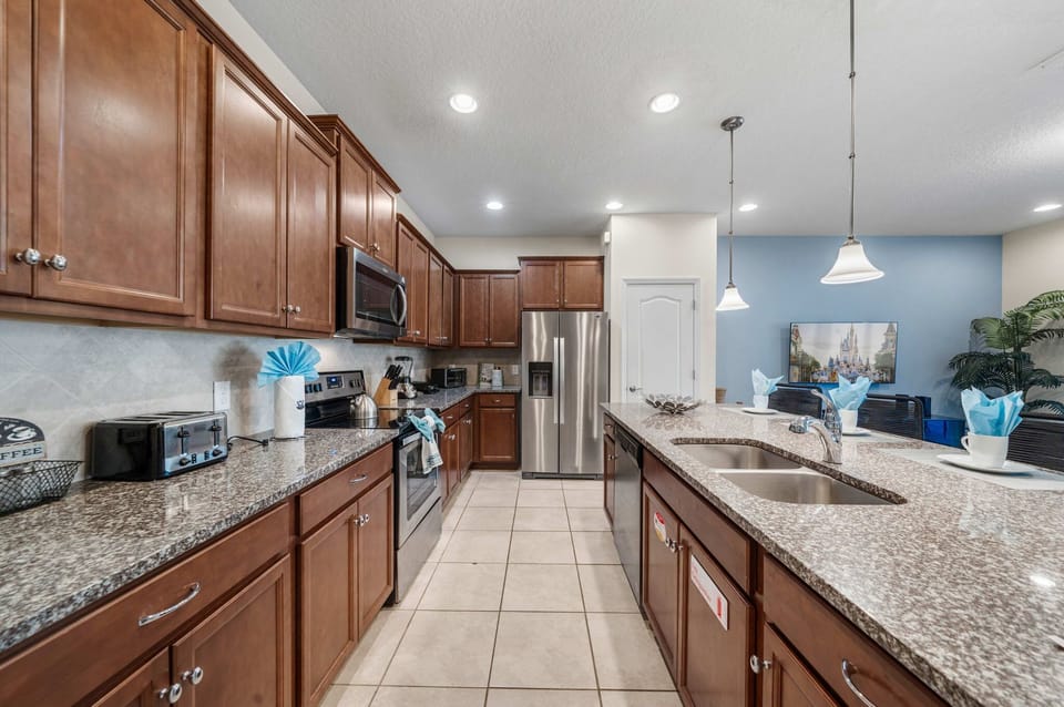 Chef-ready kitchen with expansive granite counters, double sink, stainless steel appliances, and rich wood cabinets-prep, cook, and chat around the island.