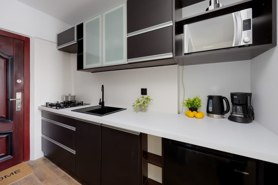 Compact kitchenette with clean, modern finishes, practical cabinetry, and countertop workspace.