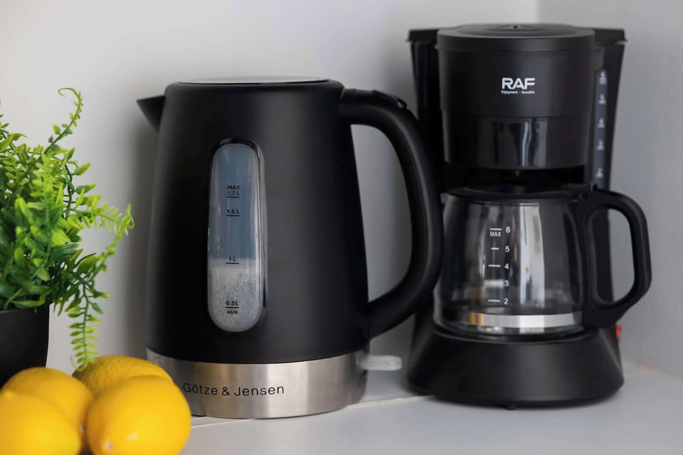 Kitchen appliances including kettle and coffee maker placed on the countertop.