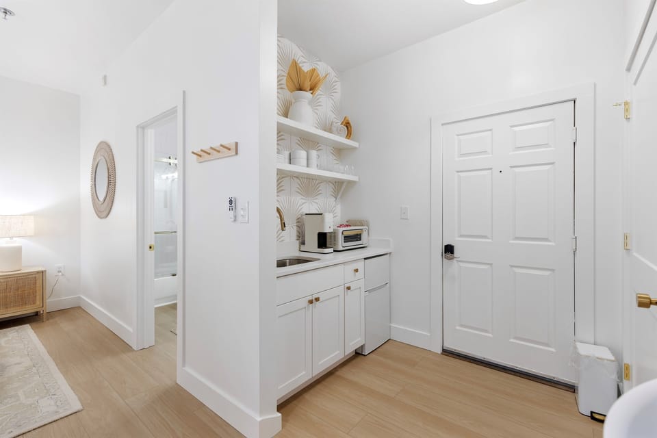 Your stylish kitchenette features white cabinetry, open shelving with chic coastal decor, and everything you need for light meals.