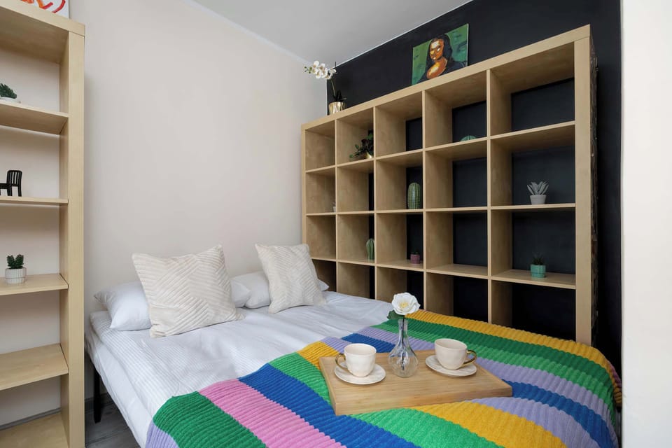 Comfortable sleeping area arranged within the studio, featuring open shelving and colorful textiles.
