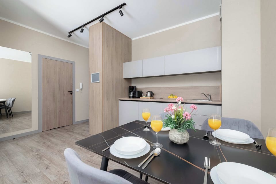 A dining area with a table set for a meal, connected to an open kitchen. The layout is modern and functional.