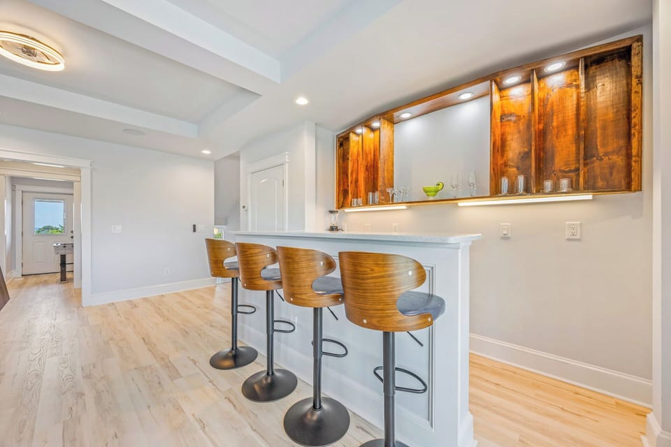 Gather around the stylish breakfast bar with its warm wood cabinetry and modern seating—perfect for your morning coffee or evening cocktails in this bright, open space.