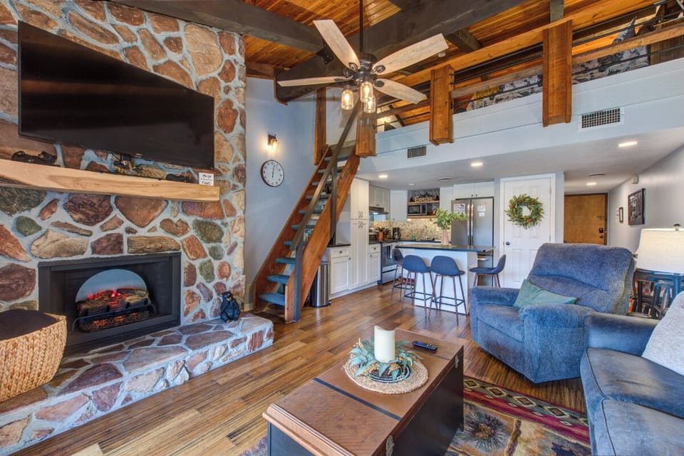 Relax by your stone fireplace in this cozy living space, where rustic wood beams and modern comfort create the perfect mountain retreat.