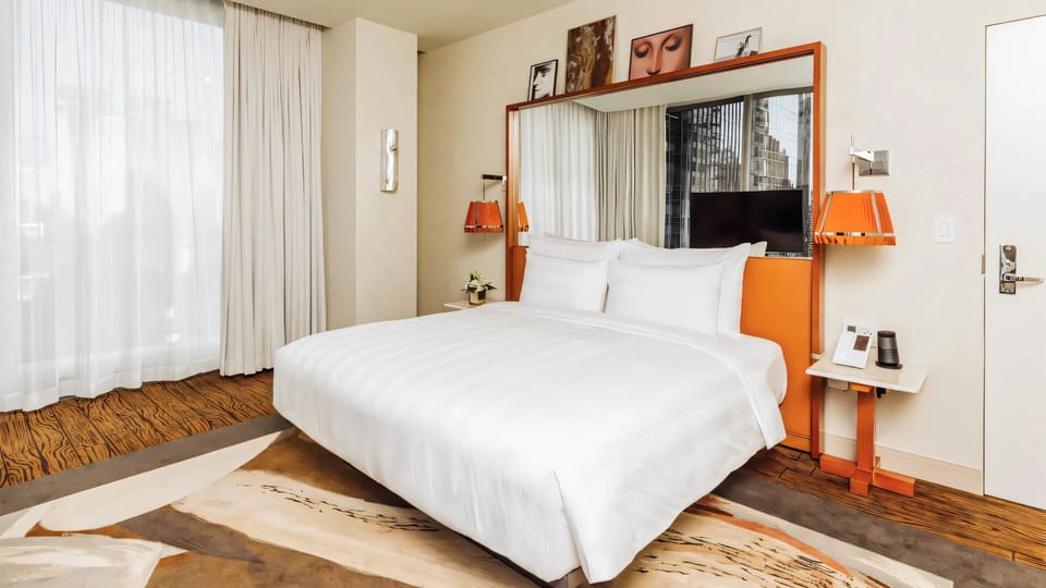 Unwind in crisp linens with soft light and city calm.