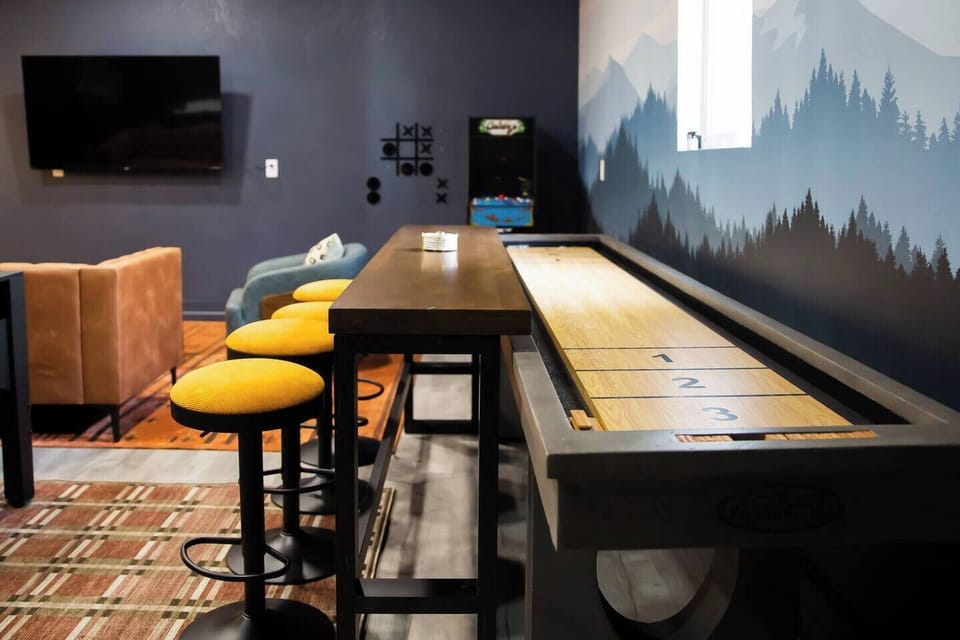 *BRAND NEW* Game room featuring shuffleboard, arcade games, 3 in 1 game table, darts, and lounge seating with smart TV
