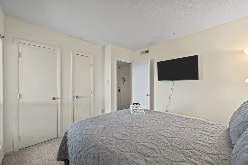 Bedroom with clean lines, ample closet space, and a wall-mounted TV for easy evenings in