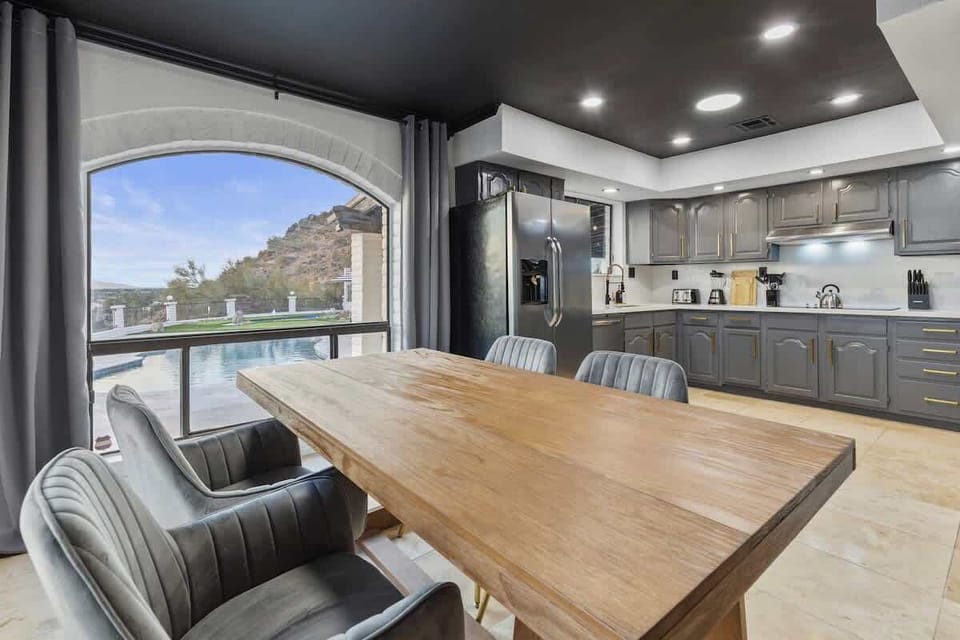 A chef-ready kitchen and dining nook with mountain and pool views—designed for slow mornings, effortless meals, and gathering without leaving the view behind.
