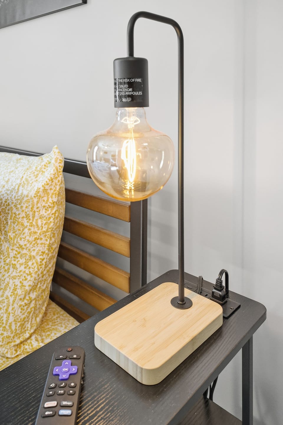 Cozy bedside nook with Edison lamp, outlet access, and soft linens