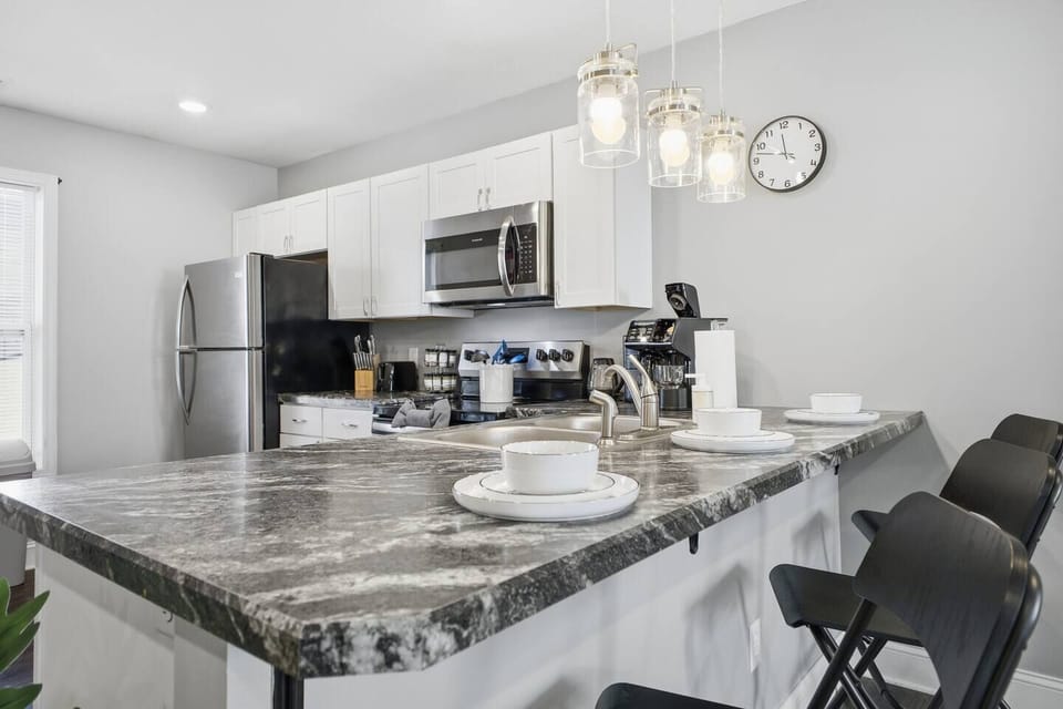 Modern kitchen with stainless appliances and breakfast bar seating for four