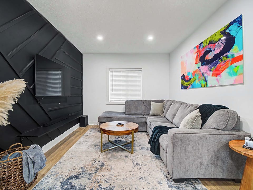 Bright living room w/ plush seating, colorful art & a sleek fireplace wall