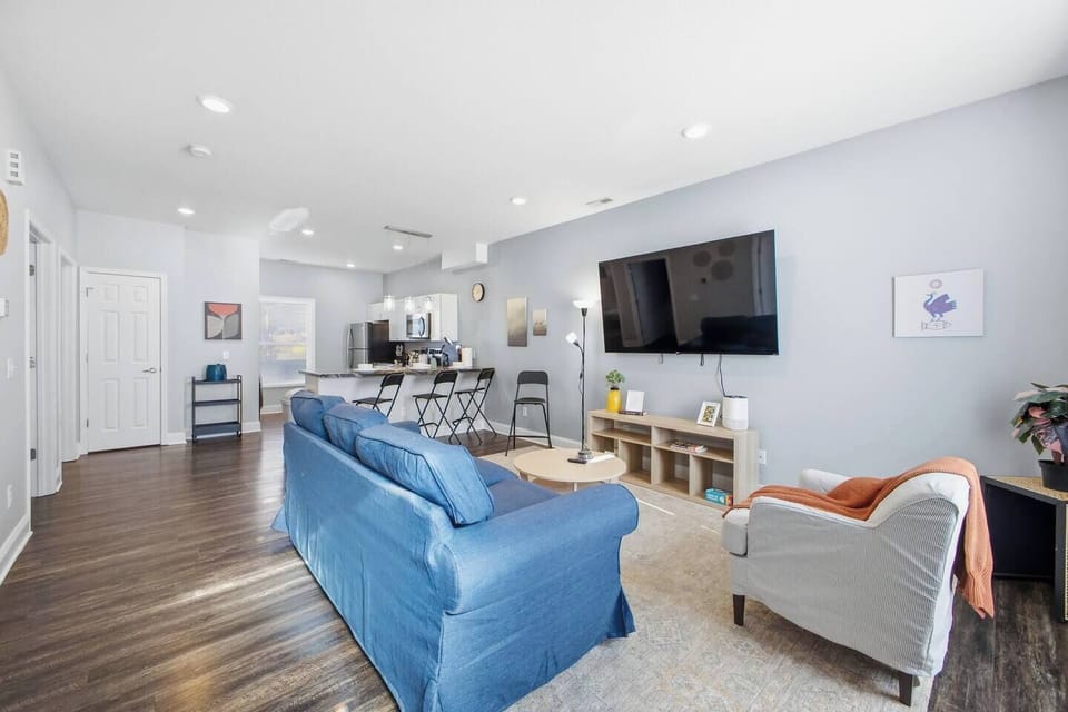 Bright open-plan living with big TV, hardwoods, and breakfast bar