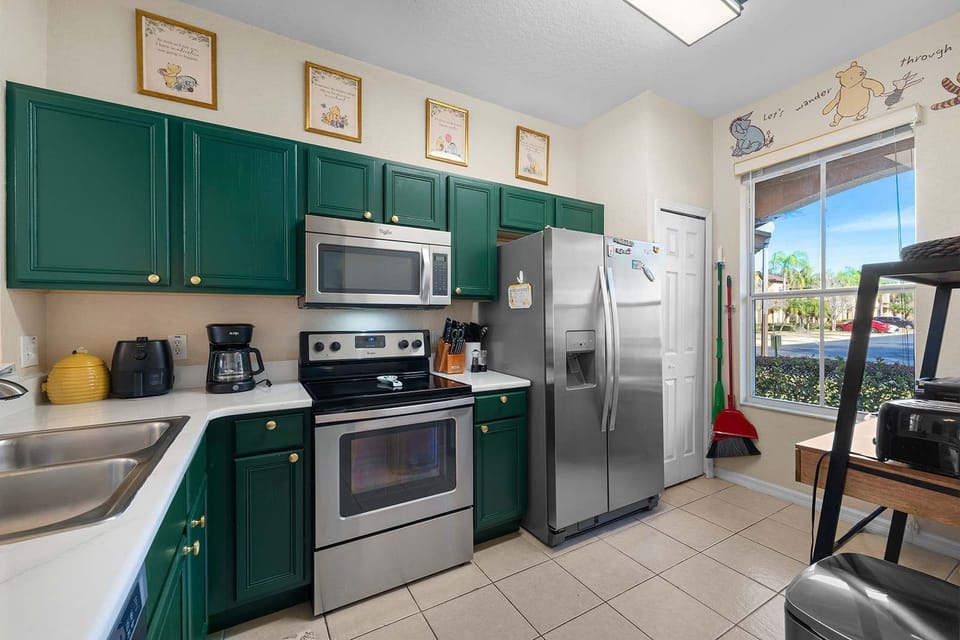 Sleek kitchen w/ green cabinetry, stainless steel appliances & plenty of prep space.
