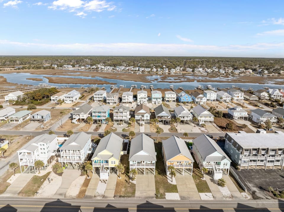 Aerial view of the home just steps from the beach. Elevated houses line quiet streets with ocean views, capturing the charm and relaxed lifestyle of a vibrant seaside community.