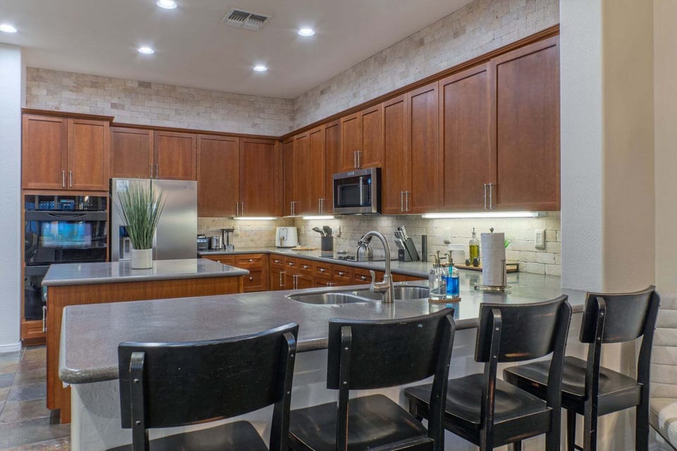 Fully stocked and modern kitchen includes 2 ovens, an island, counter seating and a breakfast nook with table seating.