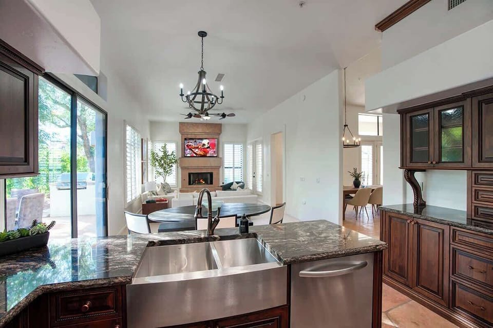 Fully equipped kitchen with stainless steel KitchenAid appliances, dual kitchen sink, a sleek kitchen island, endless counterspace, and cabinets.