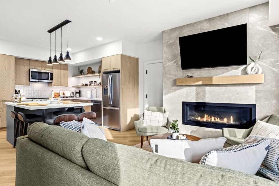 Cozy and welcoming living space featuring a fireplace, a flat-screen TV, and seamless access to a private balcony for outdoor relaxation.