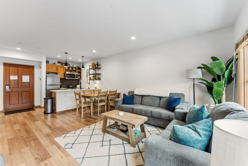 Relax in your open-concept living space featuring a cozy sectional sofa, dining area, and fully equipped kitchen—perfect for unwinding after exploring the city.