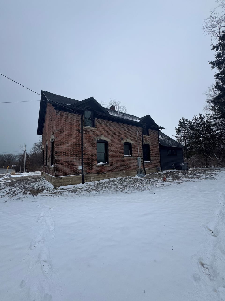 Winter retreat nestled in snowy landscape, featuring warm brick architecture and peaceful countryside setting.