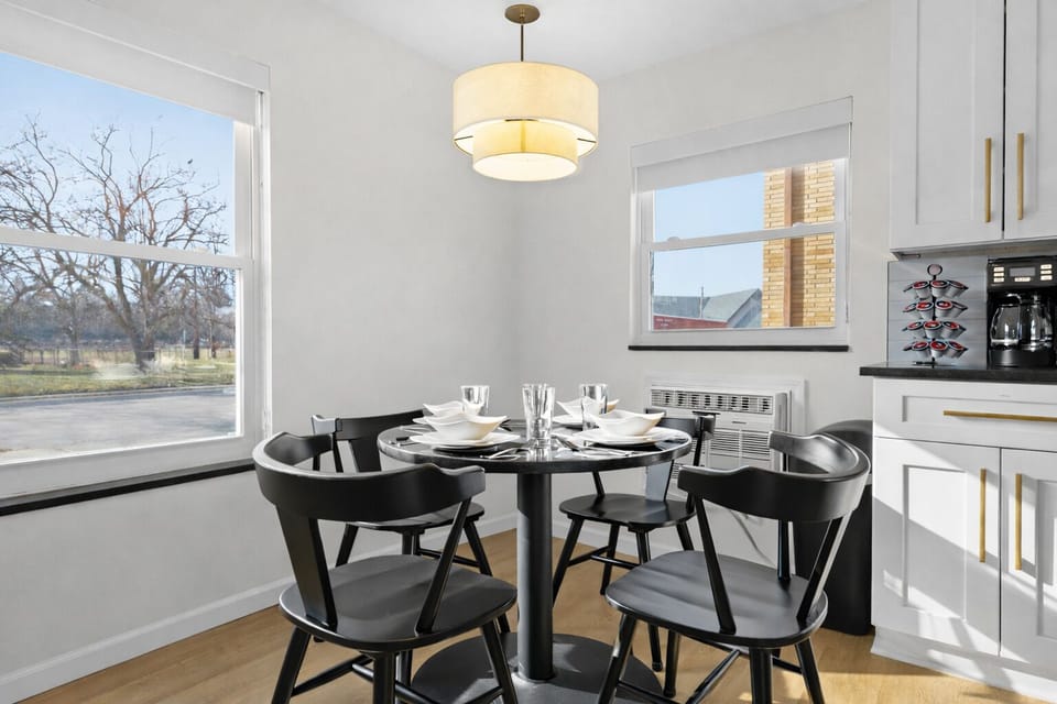 Enjoy meals in this sunlit dining area with modern seating, warm lighting, and a fully stocked kitchen—perfect for relaxed breakfasts or evening dinners.