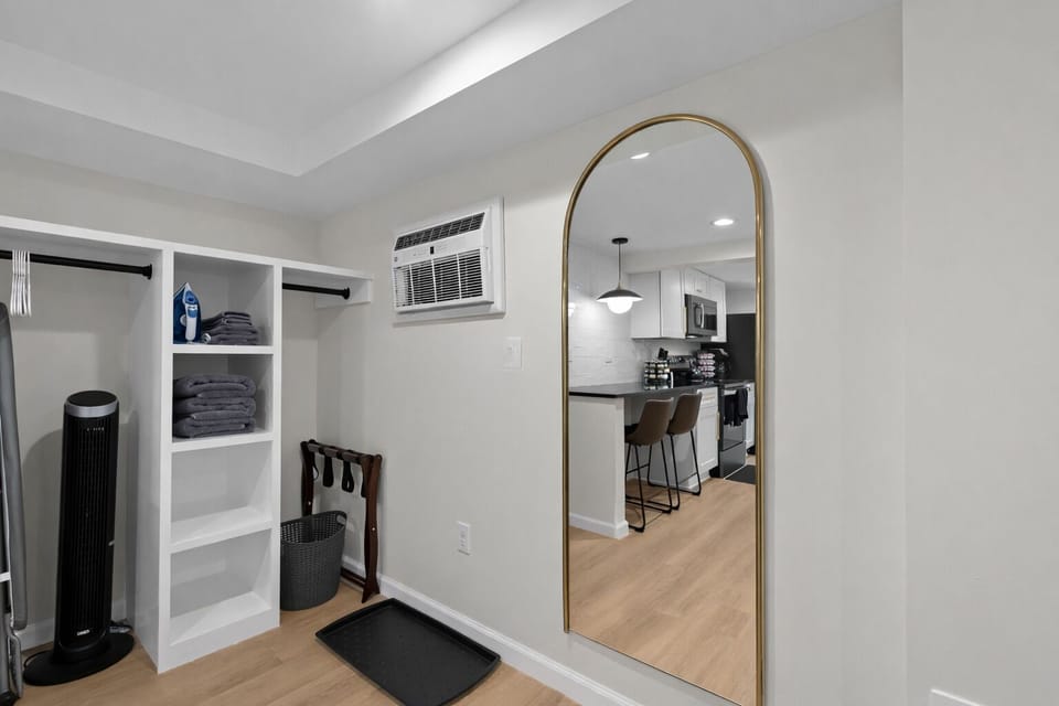 Thoughtfully designed entry space with open storage, fresh linens, full-length mirror, and a seamless flow into the modern kitchen beyond.