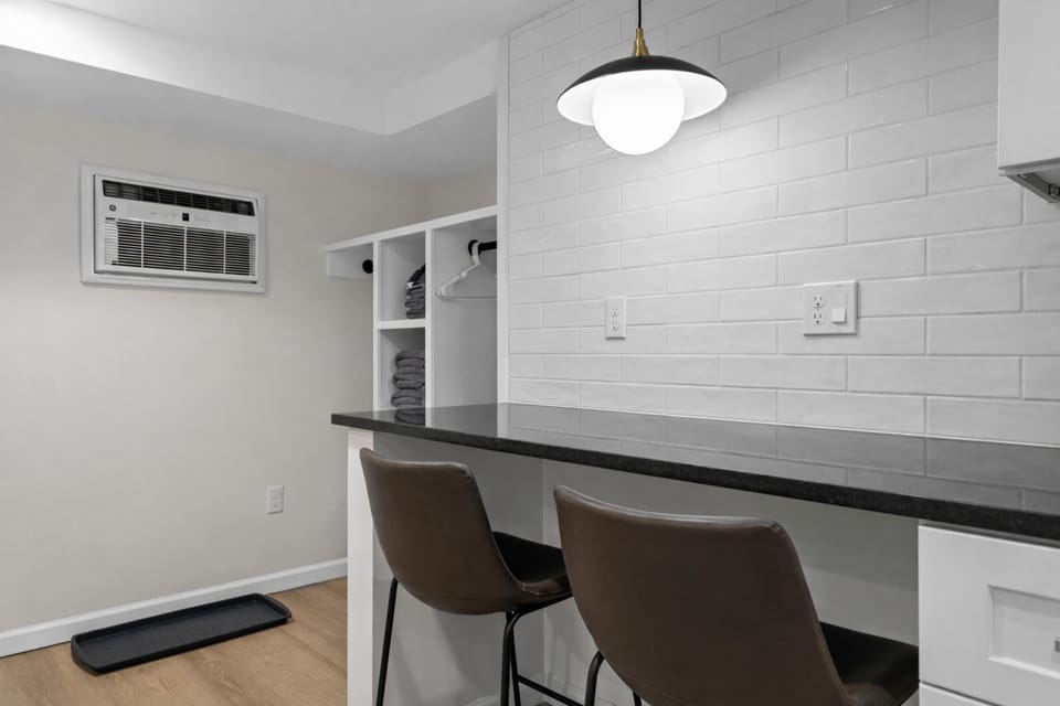 Clean, modern bar seating area with sleek countertops, stylish lighting, and open storage—perfect for casual meals, coffee breaks, or working comfortably.